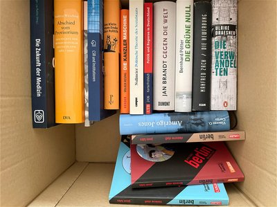 Beispielfoto für Buchspenden: Draufsicht auf einen Karton voller Bücher. Die einzelnen Titel auf den Buchrücken sind zu erkennen.