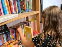 Ein Kind räumt Buchspenden ins Regal der Klassenbibliothek