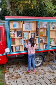 Ein Kind sucht sich Bücher aus dem Schaufenster des Büchertaxis aus