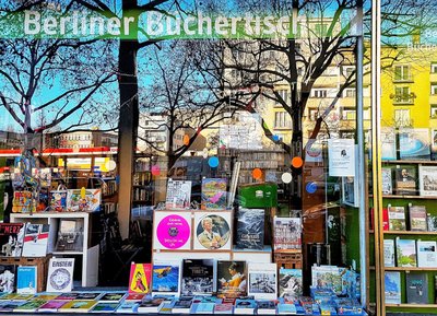 Schaufenster unserer Buchladens mit einer Auslage von Büchern und Platten mit farbenfroher Dekoration