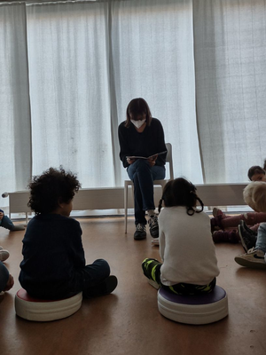 Kitakinder auf Sitzkissen hören beim Vorlesen zu