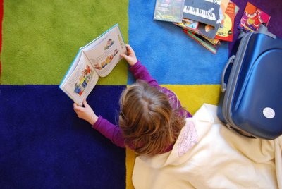 Ein Kind liest ein Buch aus dem Lesekoffer