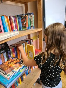 Ein Kind räumt die Buchspenden ins Regal der Klassenbibliothek